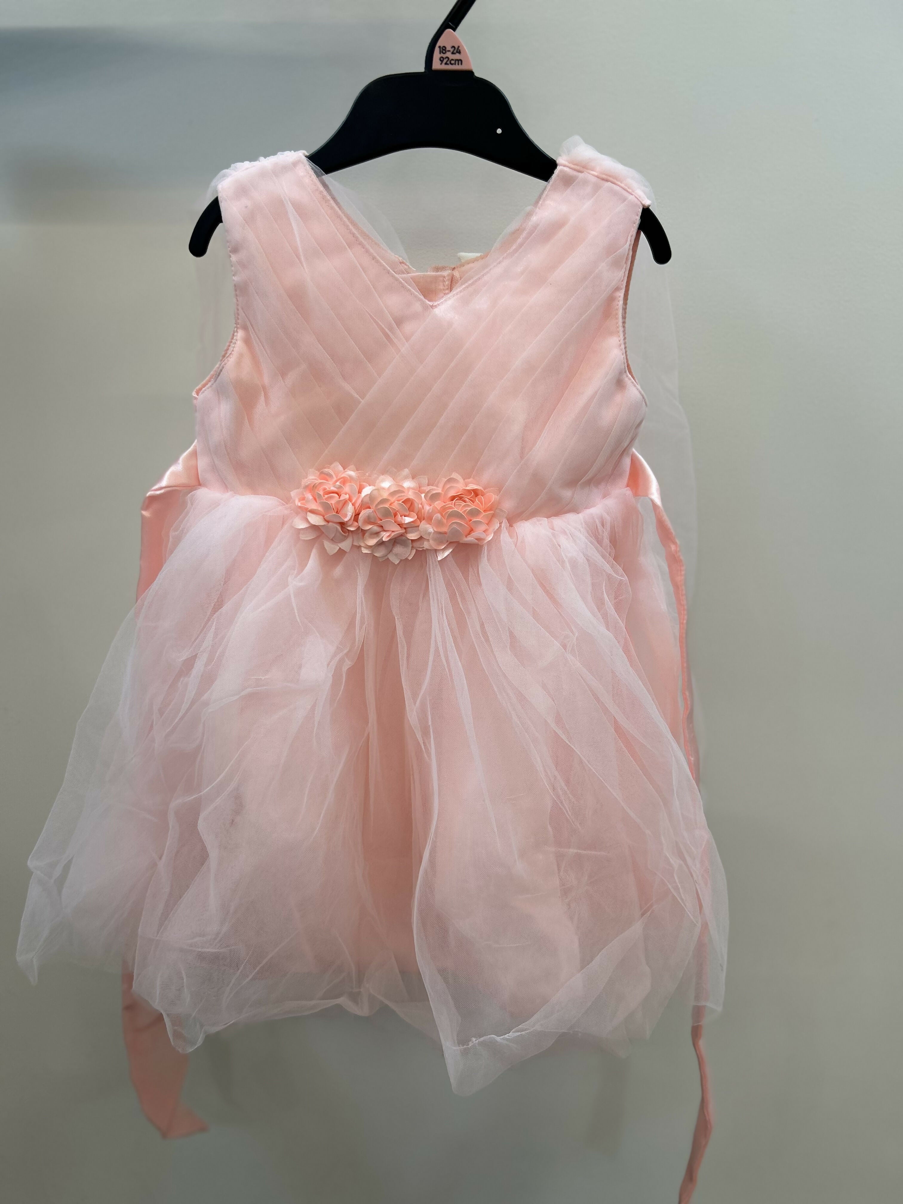 Pink dress with floral embellishments on a hanger against a plain background