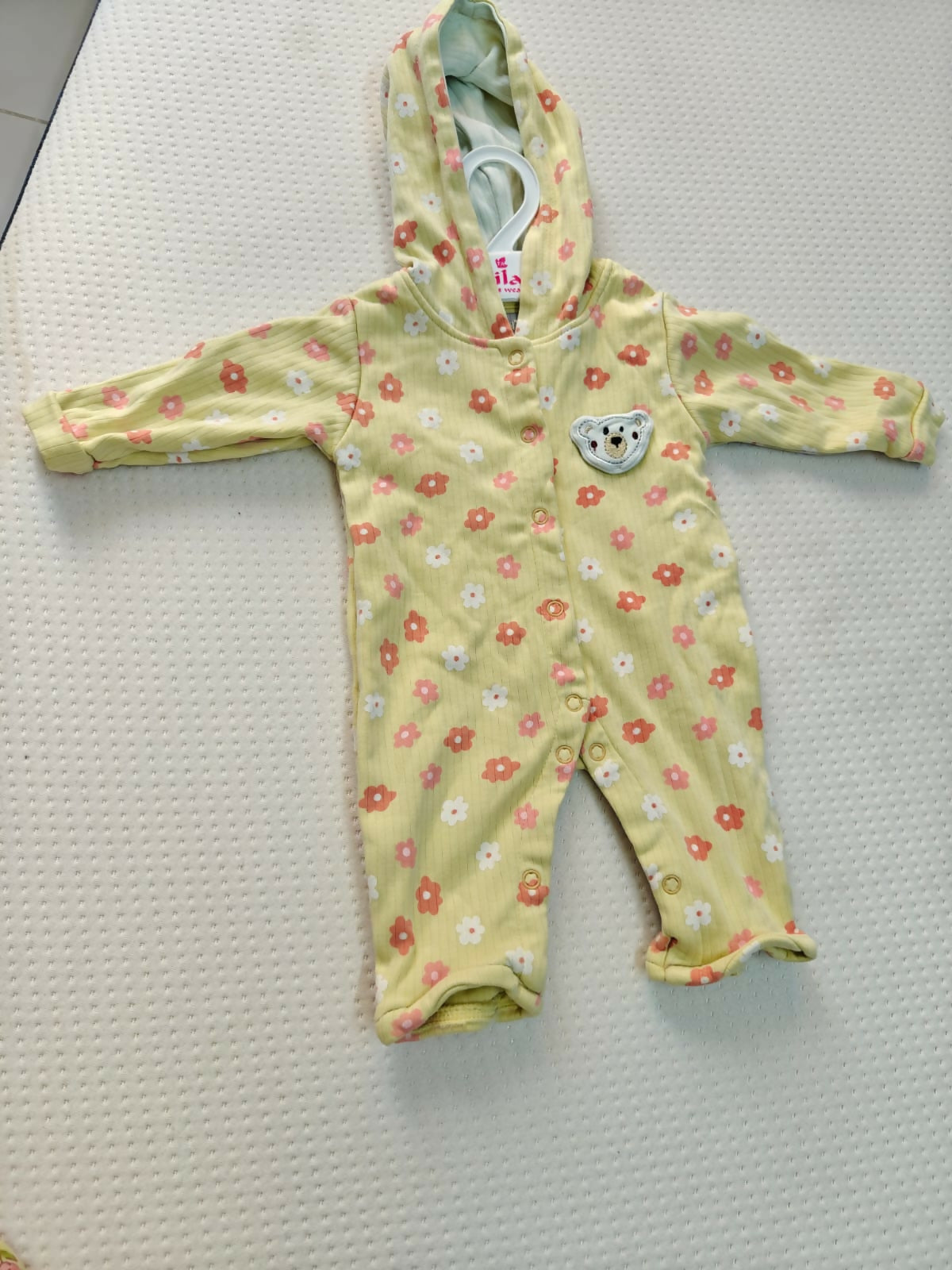 Yellow baby onesie with floral pattern on a textured surface