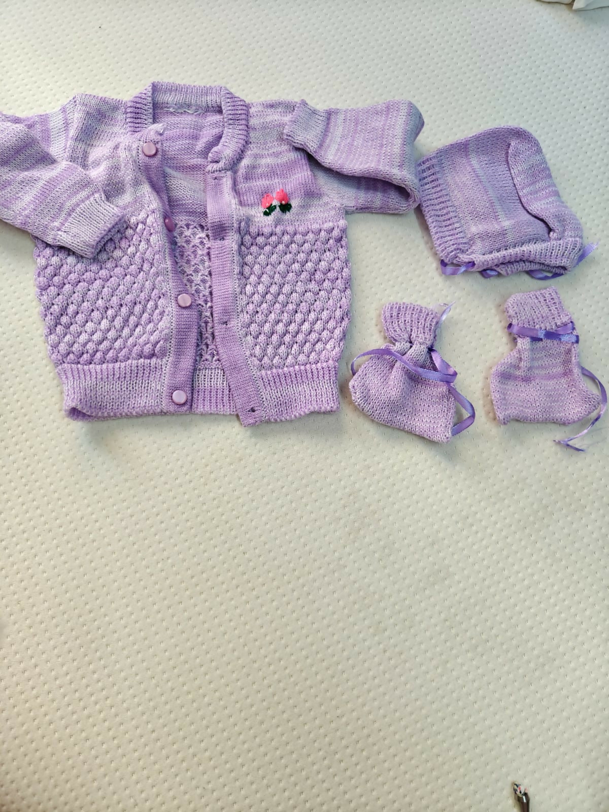 Purple baby outfit with cardigan, pants, and booties on a light background