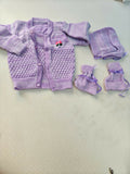 Purple baby outfit with cardigan, pants, and booties on a light background