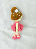Crocheted doll with a brown hat and pink dress on a white background