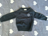 Black sweater with a logo on a gray surface with heart patterns