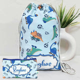 Drawstring bag and pouch with dinosaur pattern and 'Raghav' branding on a light background.