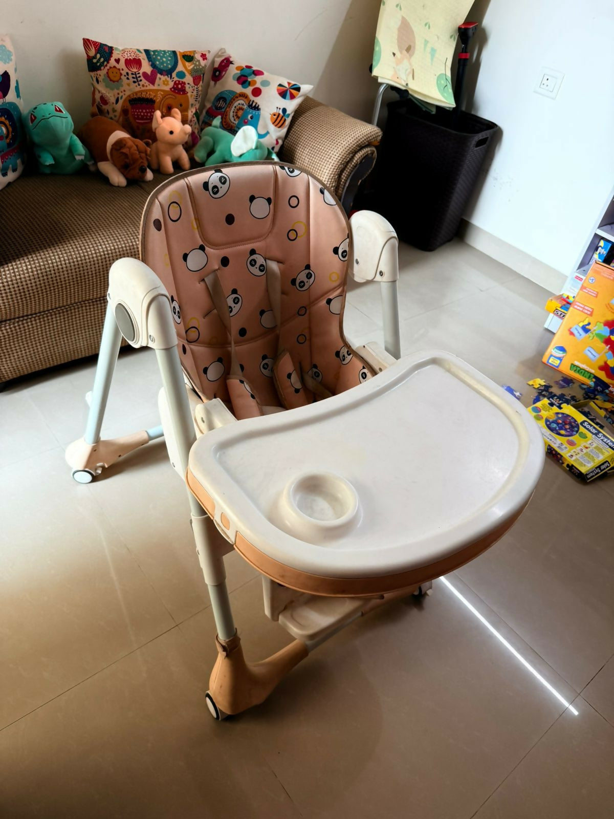 Children's high chair with patterned cushion on a tiled floor.