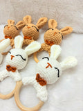 Set of crochet bunny rattle toys with wooden rings on a soft surface