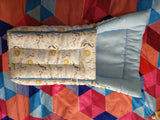 Baby crib with mattress and pillow on a colorful quilted blanket