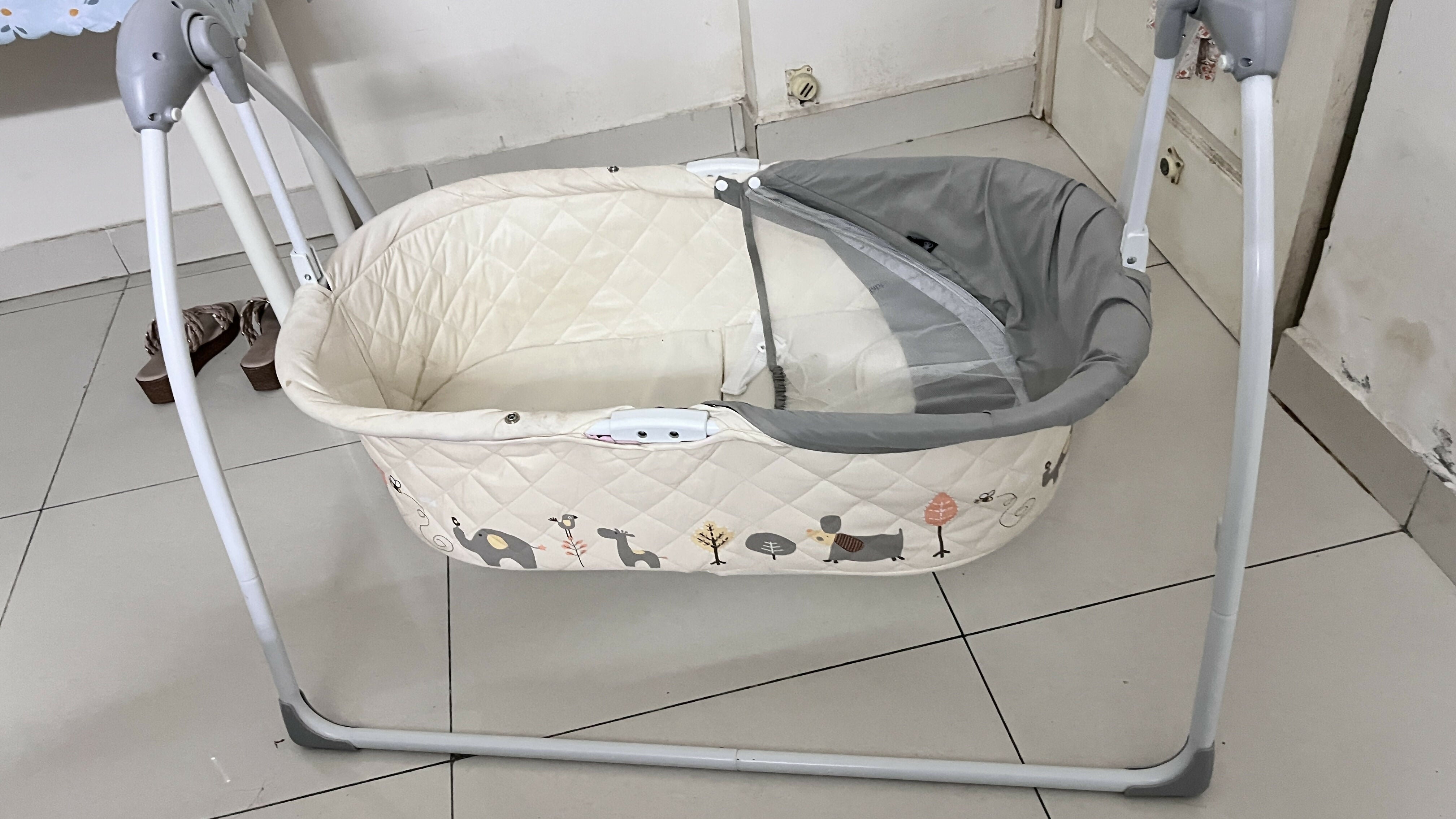 Baby swing with a cushioned seat on a tiled floor