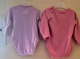 Two baby bodysuits, one purple and one pink, with white polka dots