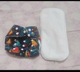 Colorful diaper with space design and white diaper cover on a light pink surface