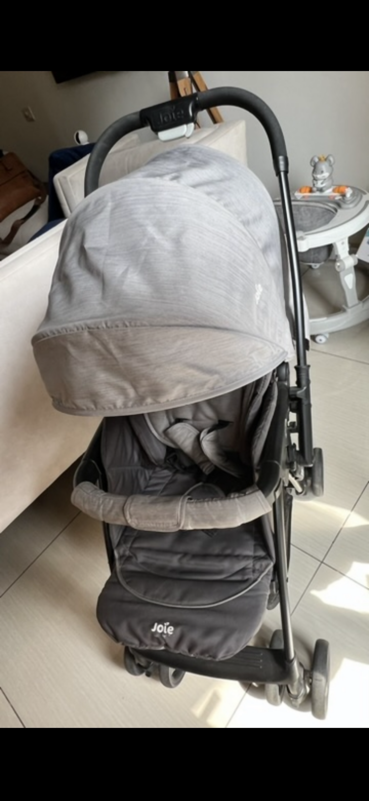 Gray stroller on a tiled floor with a table and chairs in the background