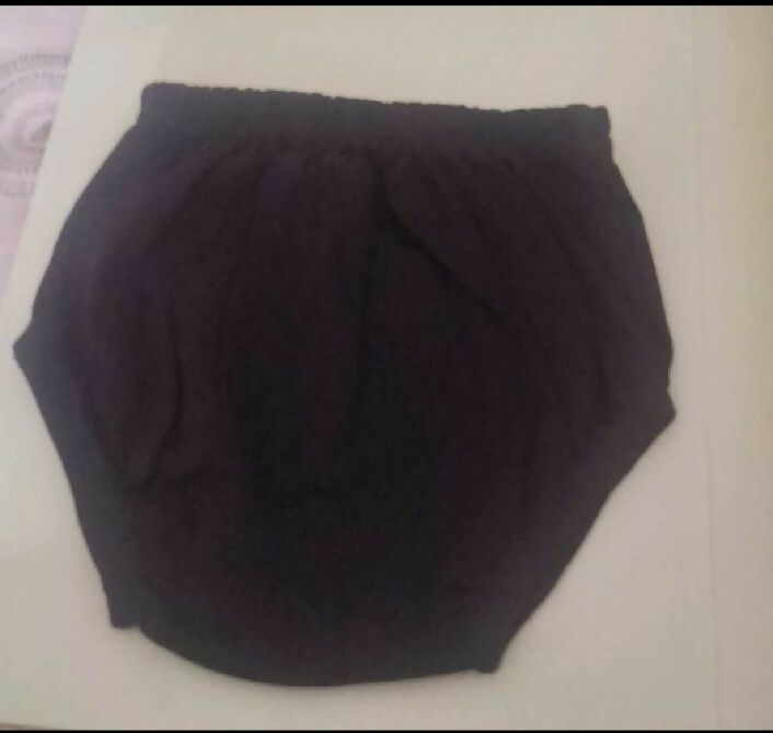 Black knitted headband on a light pink surface