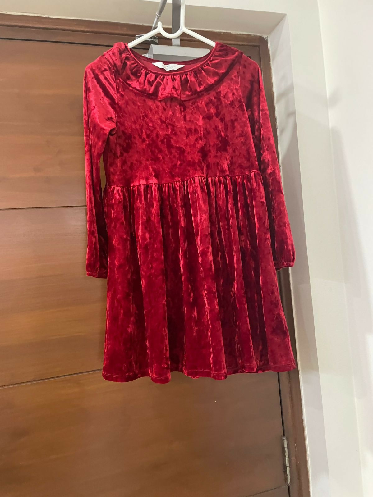 Red velvet dress hanging on a wooden door
