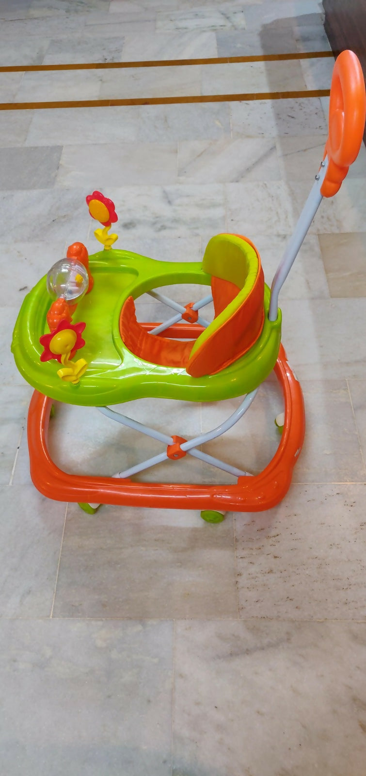 Children's walker with colorful toys on a tiled floor