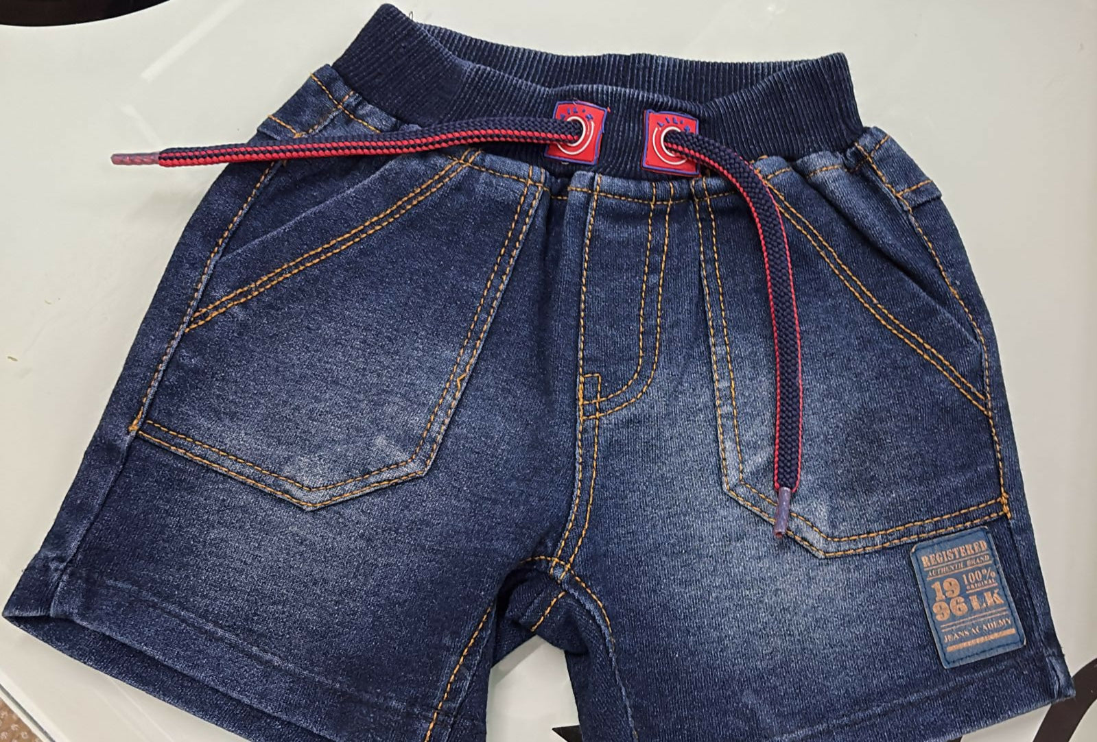 Folded blue jeans with red stitching on a white background