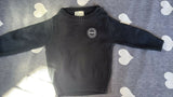 Black sweater with a logo on a gray surface with heart patterns
