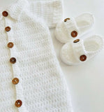White baby outfit with buttons and white baby shoes