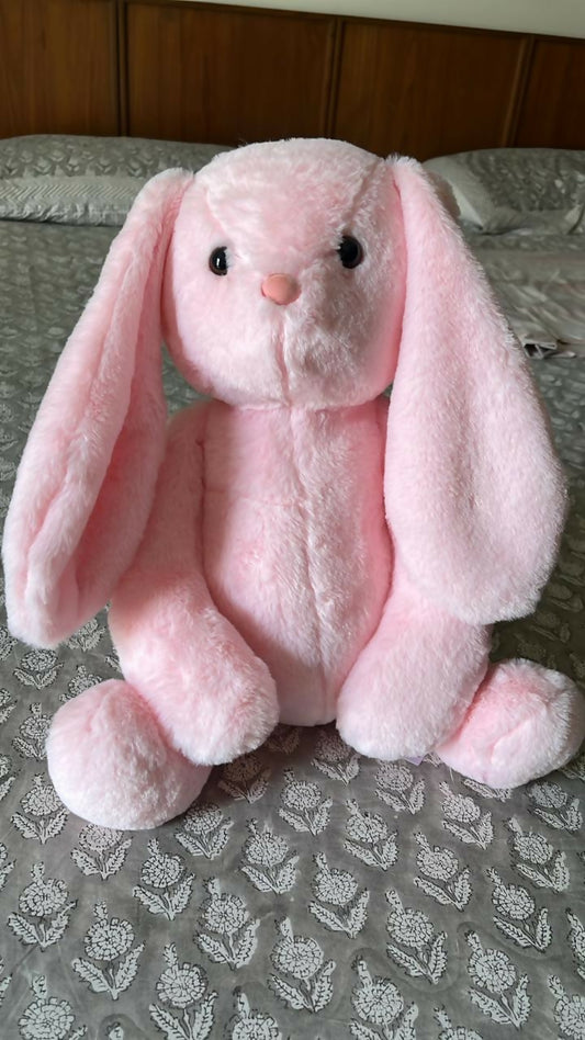 Pink plush bunny toy on a patterned surface