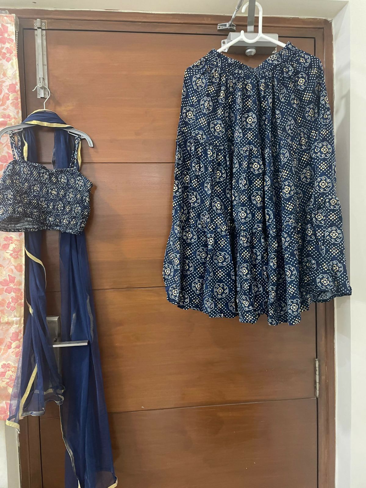 Blue patterned top and skirt set hanging on a wooden door.