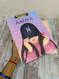 Notebook with a cover featuring an illustration of a person wearing a cap, held by a hand on a wooden surface.
