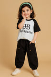 Child wearing a black and white shirt with text and black pants