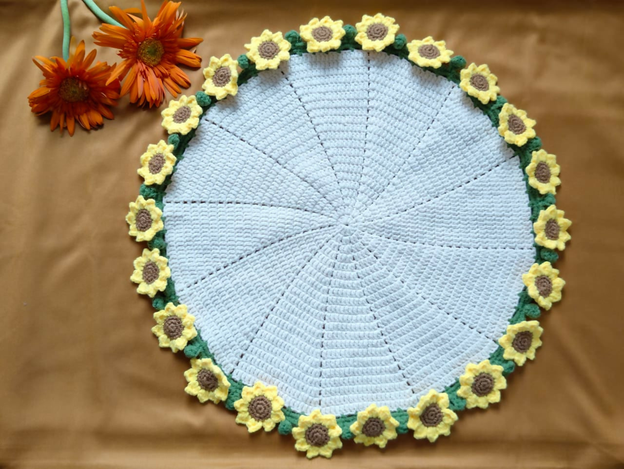 Round crochet mat with sunflower design on a brown background