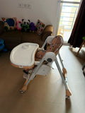 Baby high chair in a room with a couch and toys.