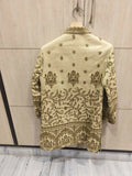 Embroidered traditional jacket on a hanger against a light wooden panel background