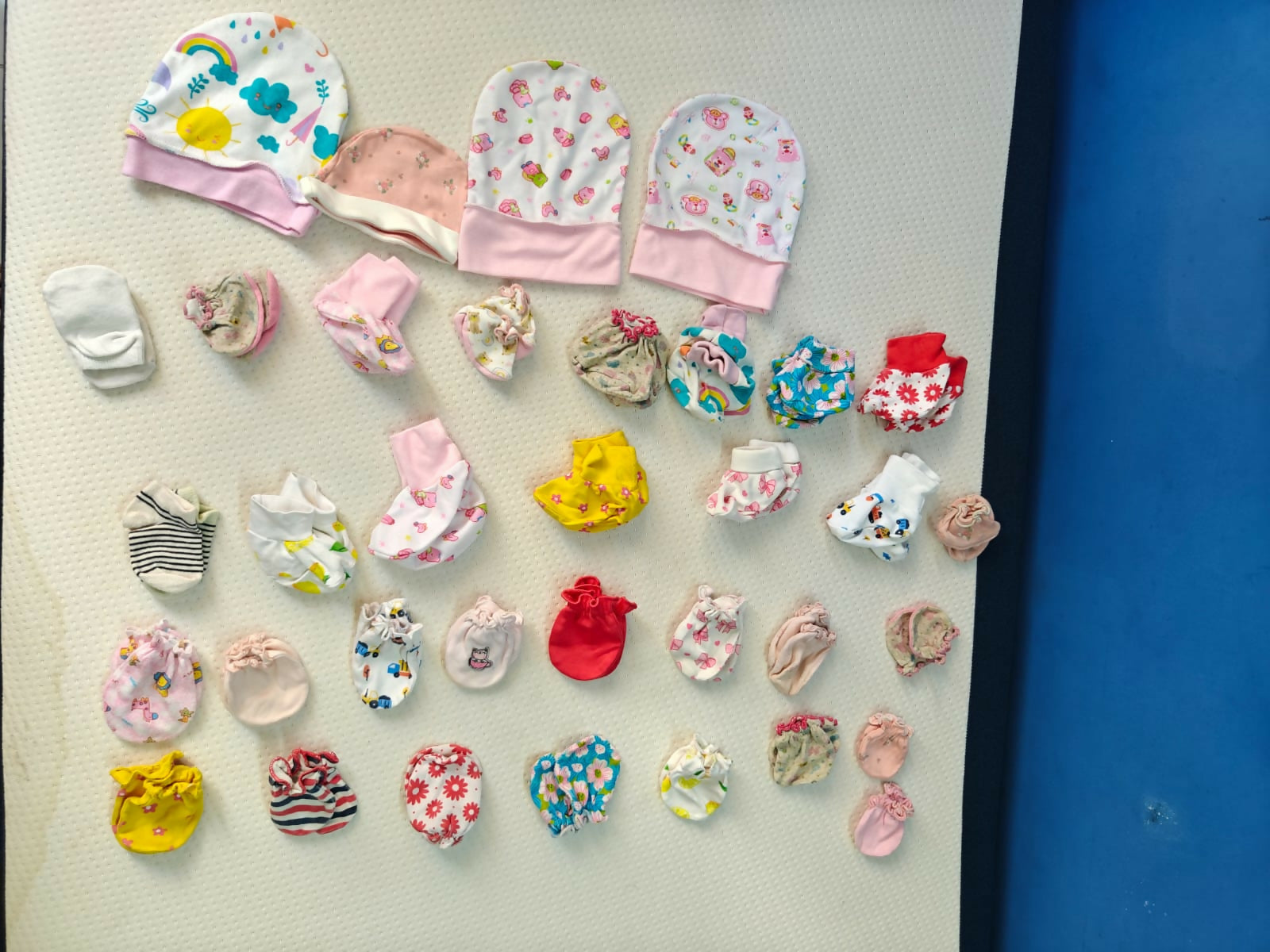 Collection of colorful baby hats and booties on a white surface with a blue background