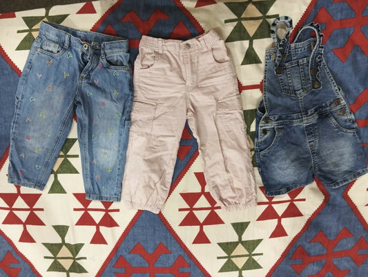Three pairs of children's pants on a patterned rug