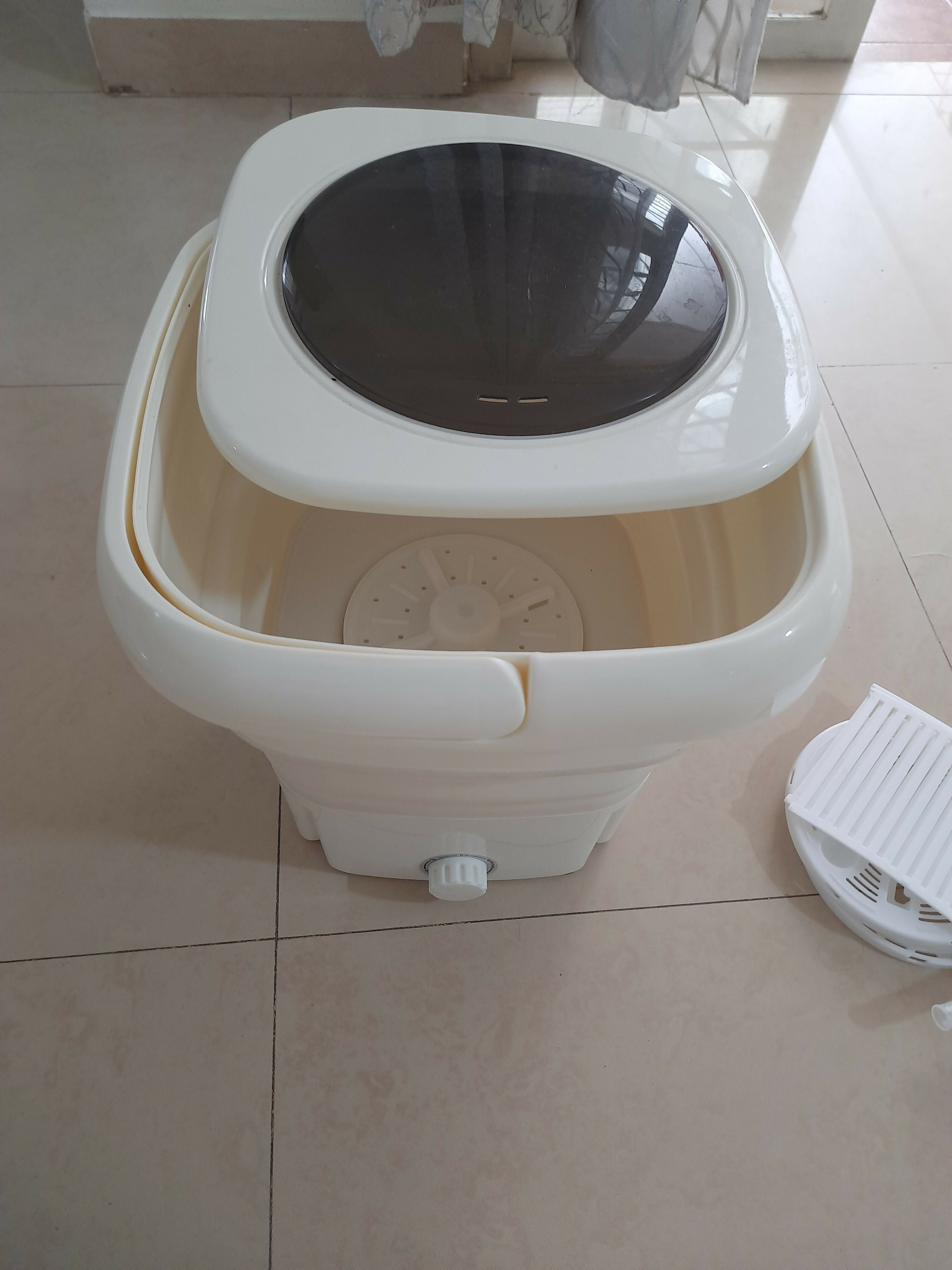 White and beige portable washing machine on a tiled floor