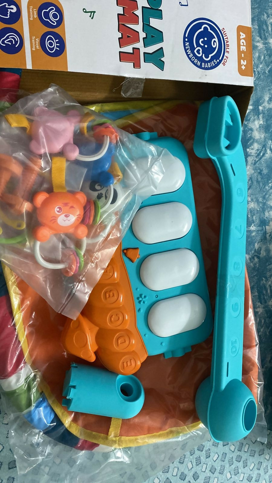 Colorful baby toy with various shapes and letters on a textured surface