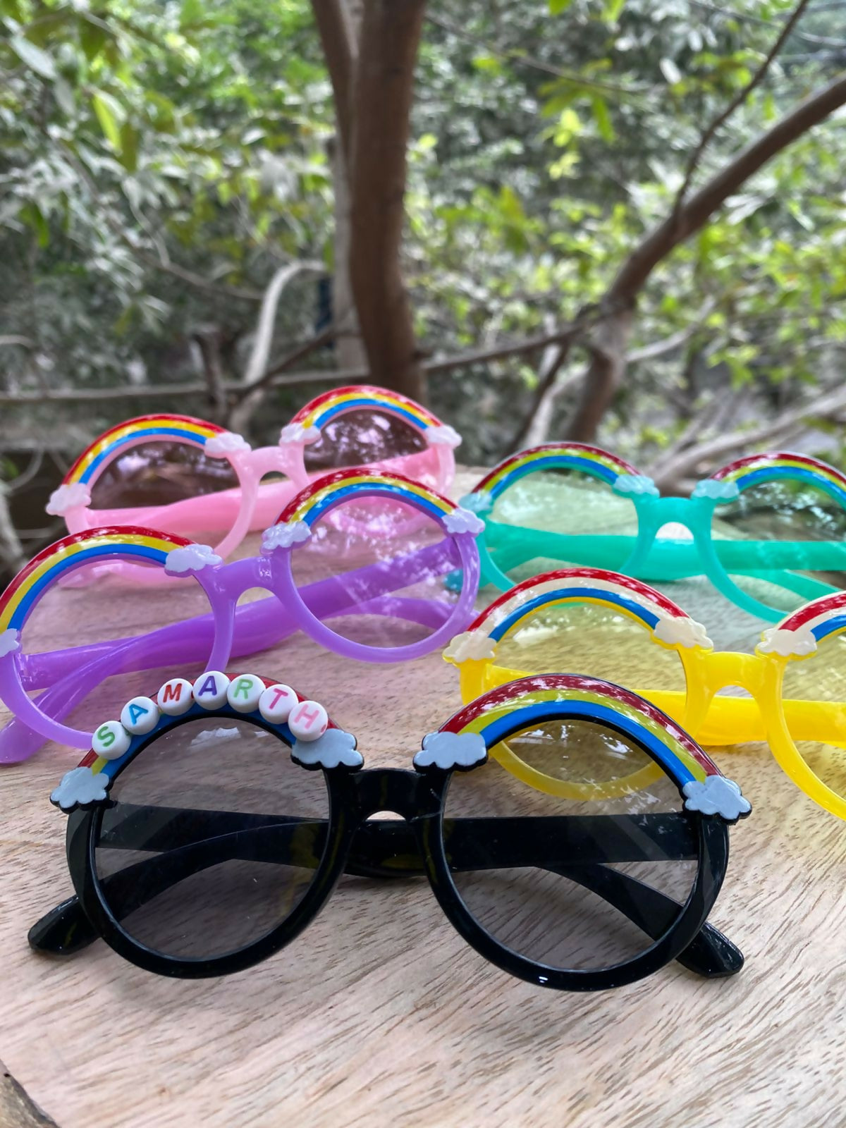 Colorful sunglasses with rainbow frames on a wooden surface with a natural background