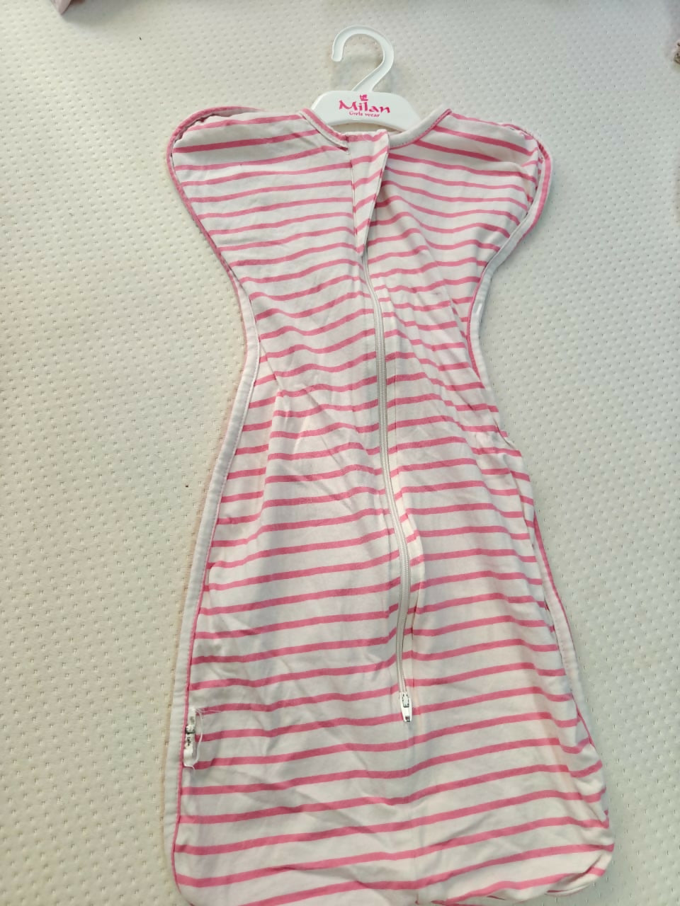 Striped dress on a hanger with 'Milan' label on a textured surface