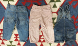 Three pairs of children's pants on a patterned rug