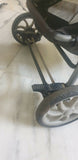 Close-up of a stroller wheel and metal frame on a light background
