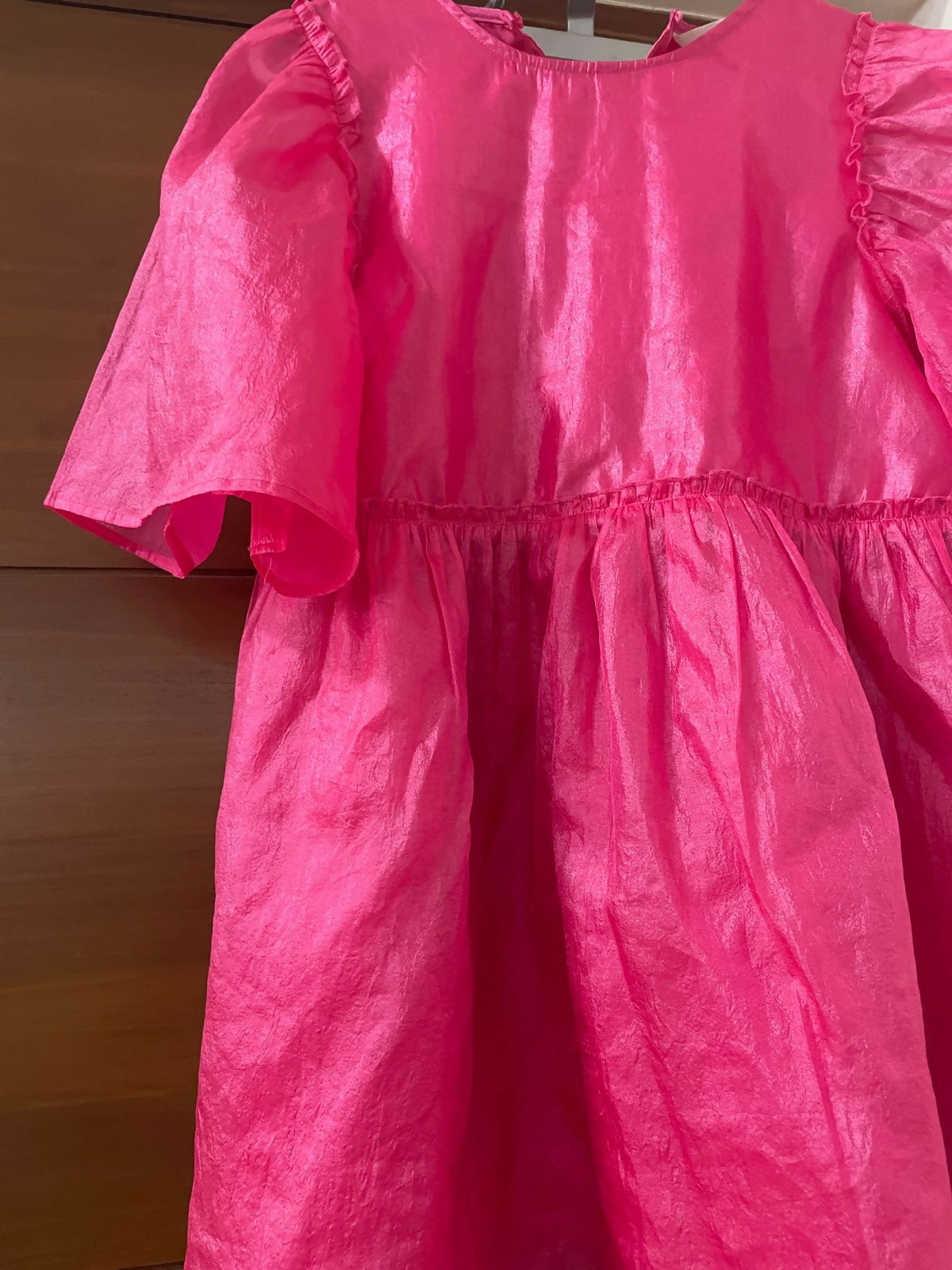 Pink dress with ruffled sleeves on a wooden background