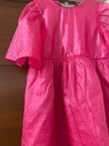Pink dress with ruffled sleeves on a wooden background