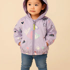 Child wearing a light purple jacket with colorful patches 