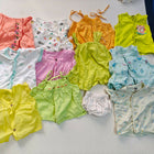Collection of colorful baby clothes on a white surface
