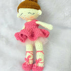 Crocheted doll with a pink dress, yellow shoes, and brown hat on a white background