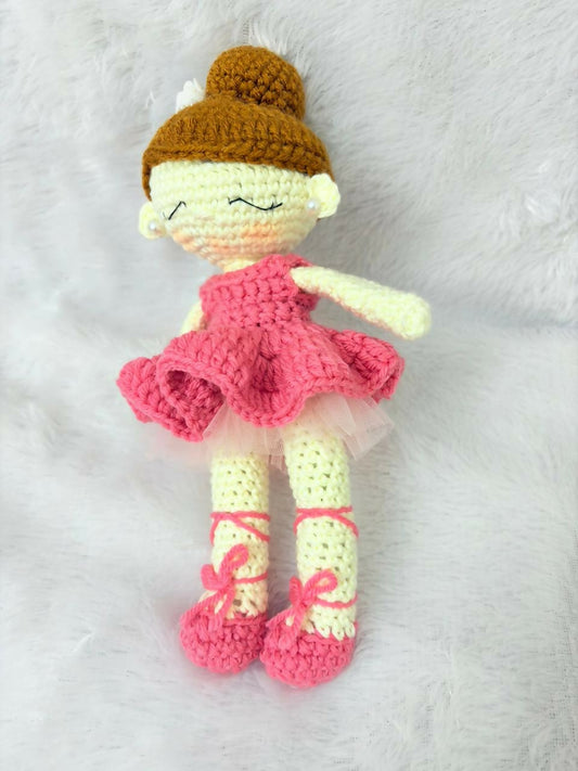 Crocheted doll with a pink dress, yellow shoes, and brown hat on a white background