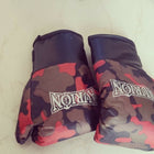 Camouflage-patterned boxing gloves with 'Nomix' branding on a light-colored floor.