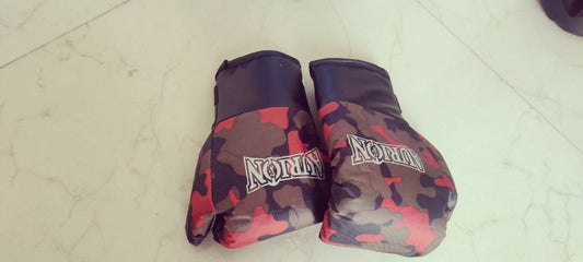 Camouflage-patterned boxing gloves with 'Nomix' branding on a light-colored floor.
