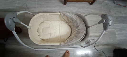 Baby swing on a tiled floor with a person's foot visible