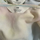 Close-up of an H&M label on a garment with a pastel tie-dye pattern.