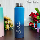 Blue water bottle with 'Sakshi' branding on a wooden surface with flowers in the background