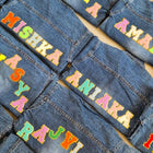 Denim jackets with colorful text labels on a flat surface