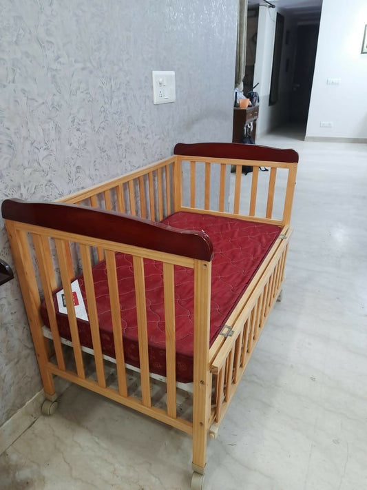 Wooden crib with red mattress 