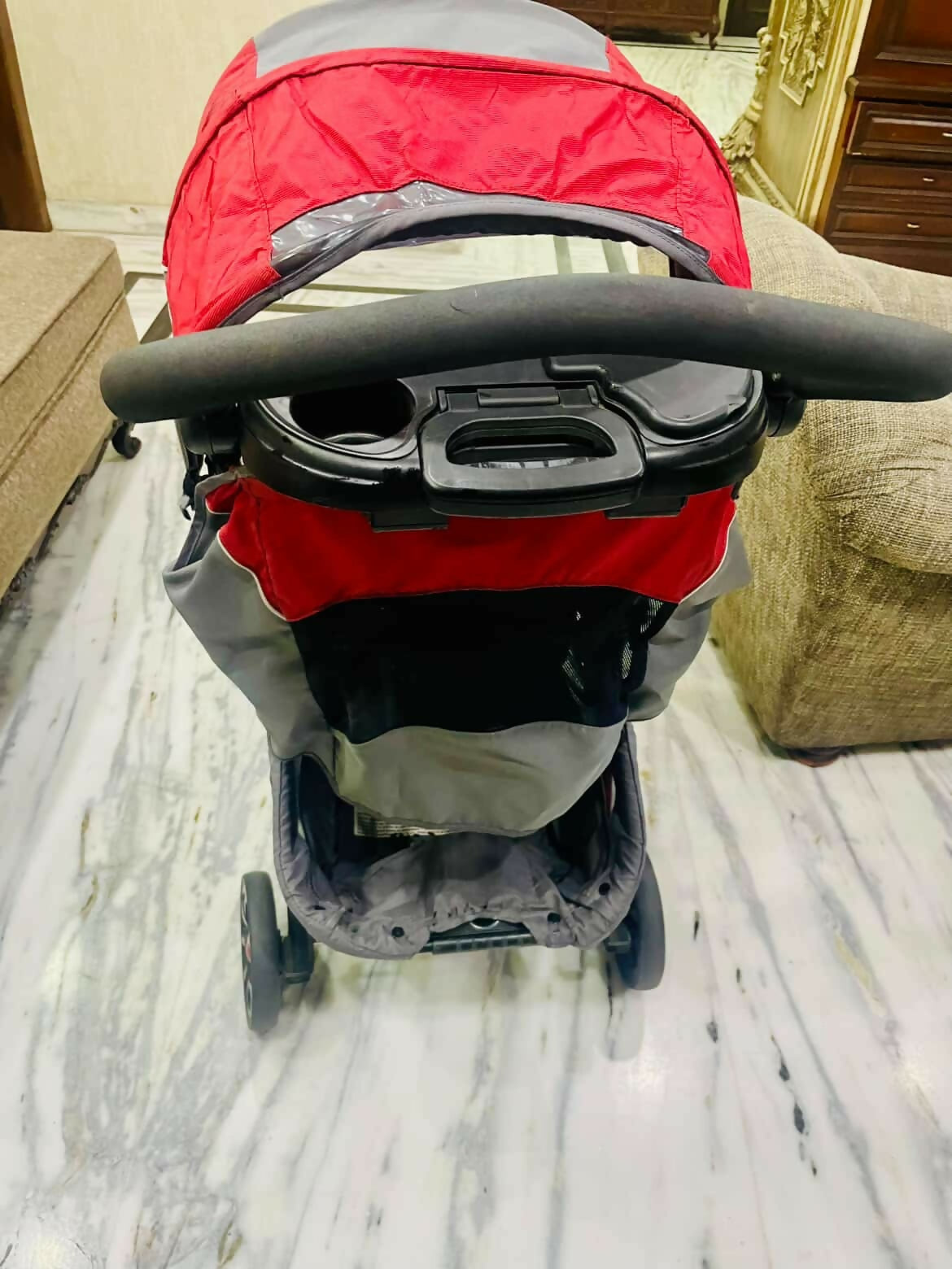 Red and gray stroller on a marble floor