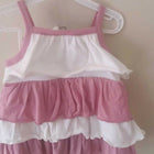Pink and white dress on a hanger against a beige wall